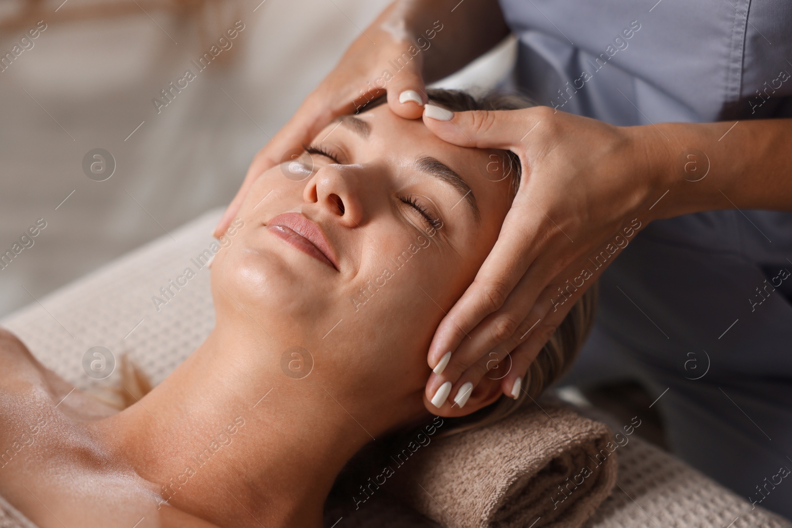 Beautiful woman receiving facial massage on couch in spa salon, closeup Photo of Beautiful woman receiving facial massage on couch in spa salon, closeup