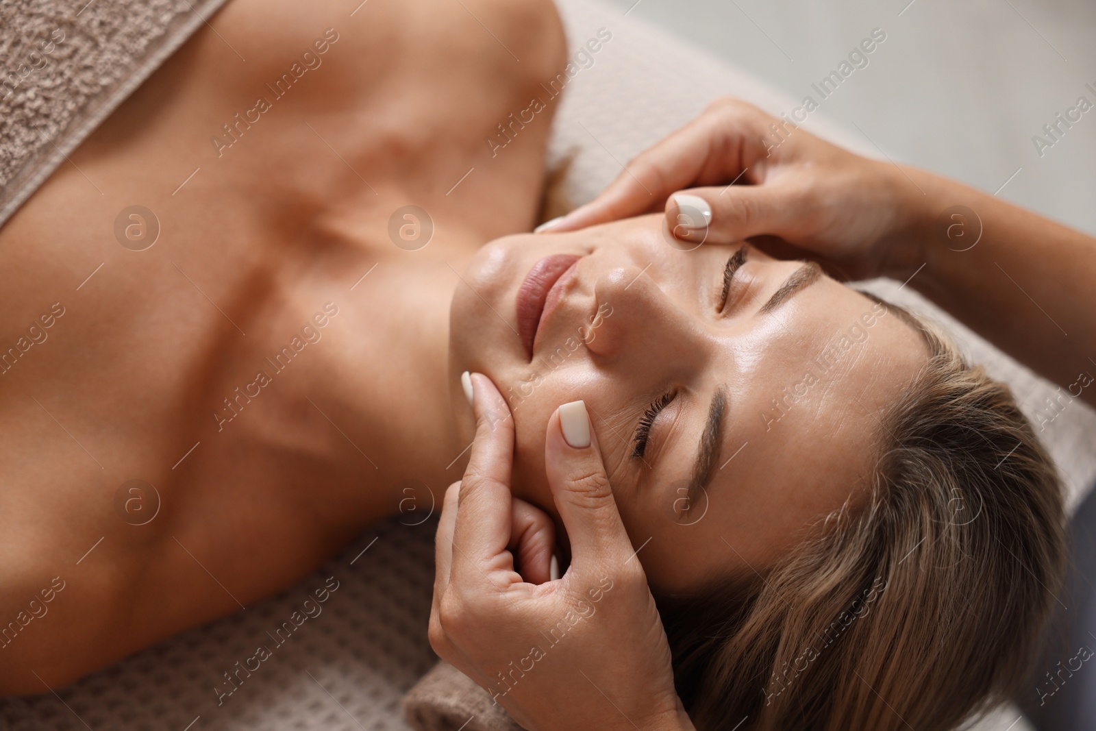 Beautiful woman receiving facial massage on couch indoors, closeup Photo of Beautiful woman receiving facial massage on couch indoors, closeup