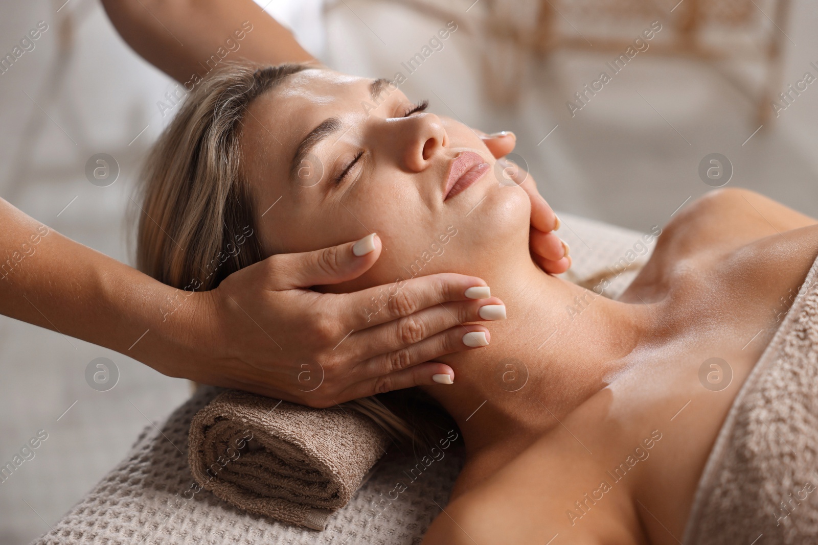Beautiful woman receiving facial massage on couch in spa salon, closeup Photo of Beautiful woman receiving facial massage on couch in spa salon, closeup
