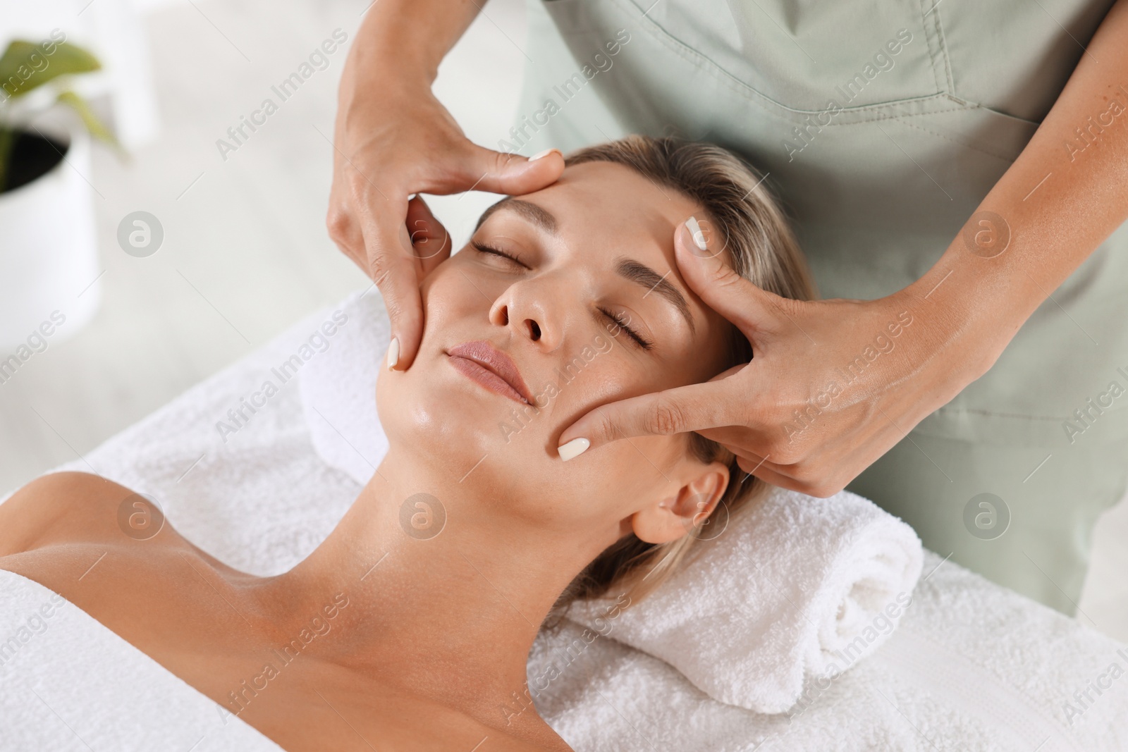 Beautiful woman receiving facial massage on couch in spa salon, closeup Photo of Beautiful woman receiving facial massage on couch in spa salon, closeup