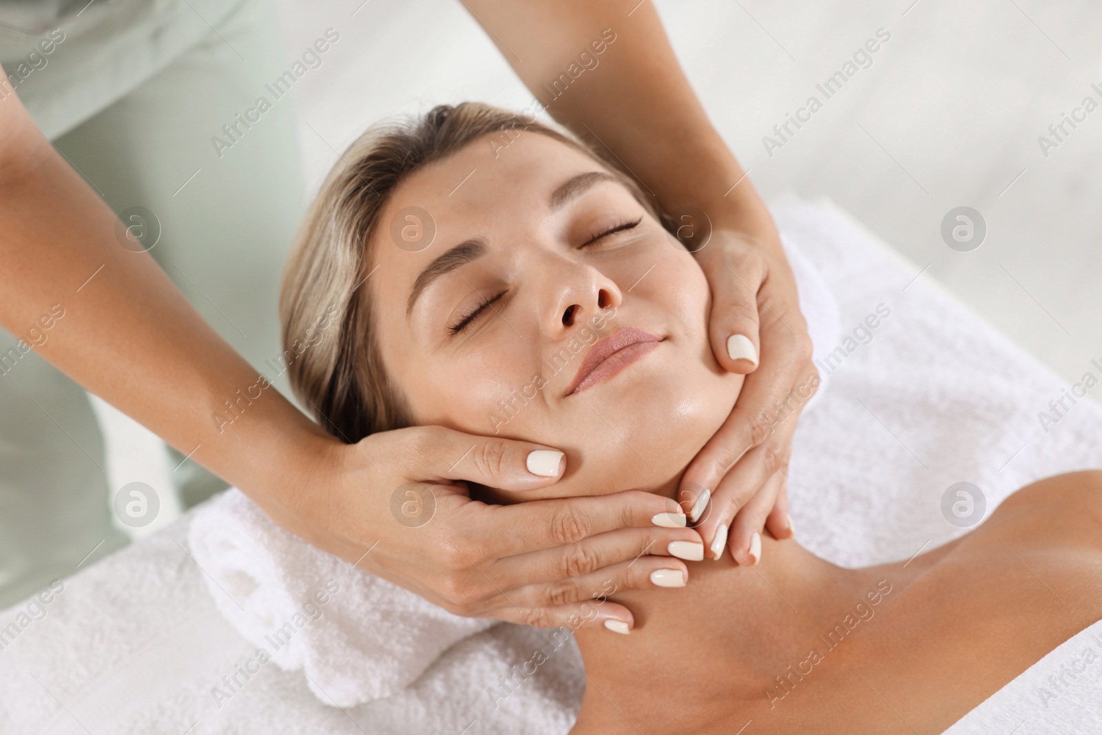 Beautiful woman receiving facial massage on couch indoors, closeup Photo of Beautiful woman receiving facial massage on couch indoors, closeup