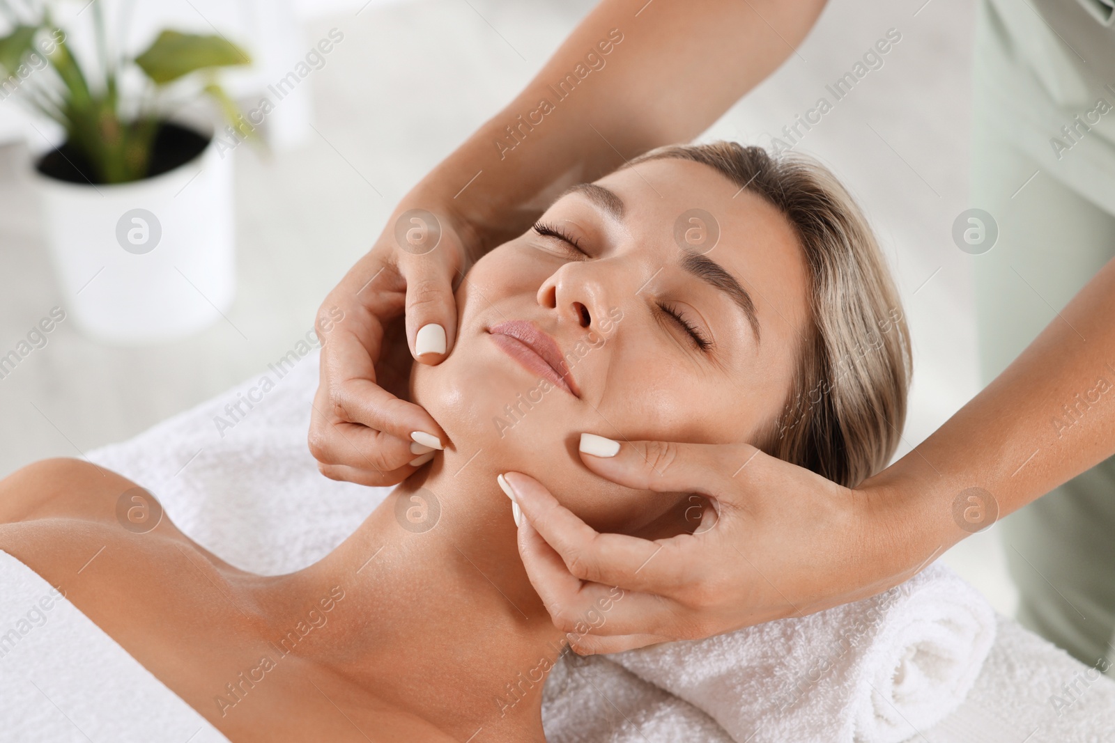 Beautiful woman receiving facial massage on couch indoors, closeup Photo of Beautiful woman receiving facial massage on couch indoors, closeup