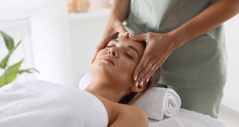 Photo of Beautiful woman receiving facial massage on couch indoors, closeup