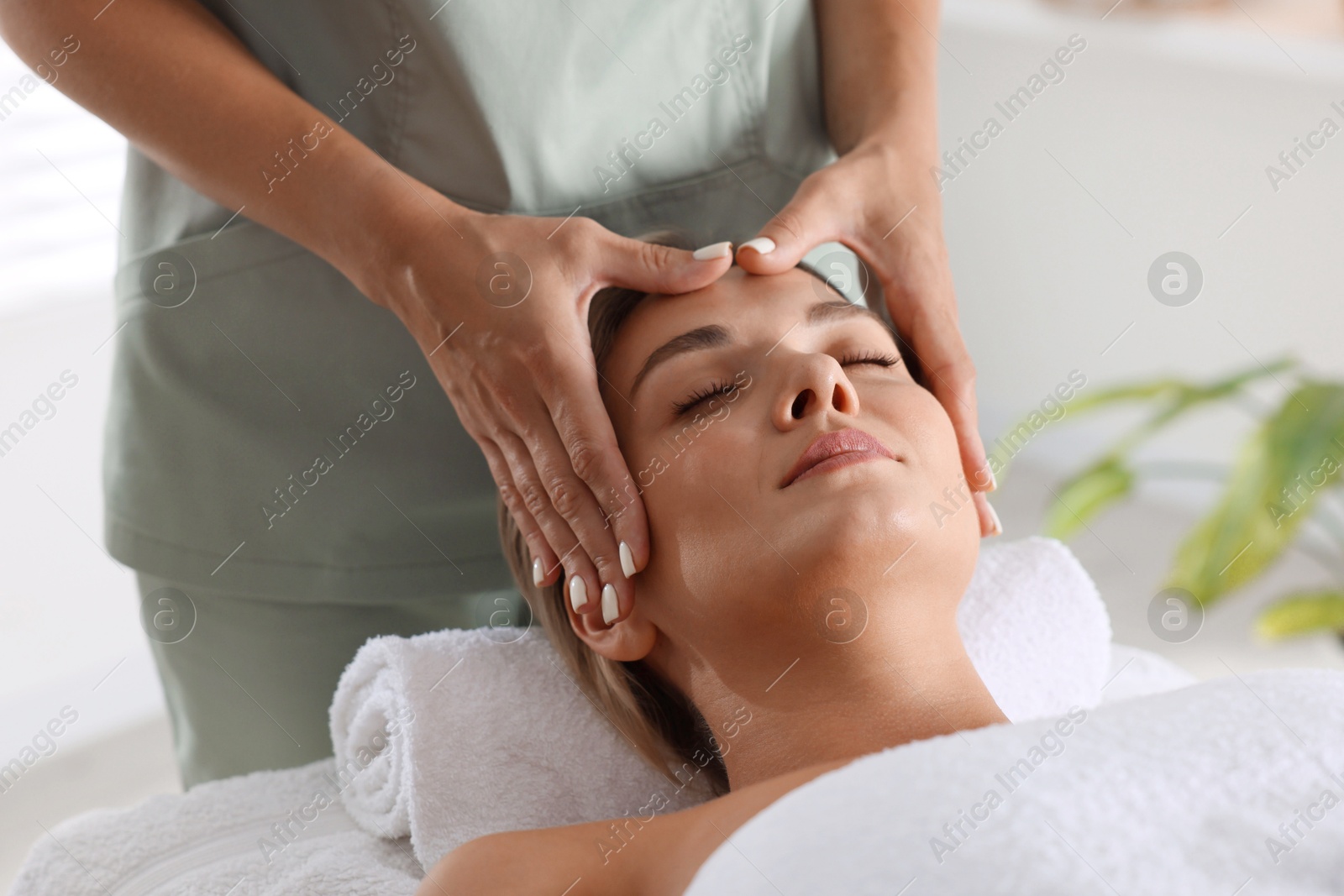Beautiful woman receiving facial massage on couch indoors, closeup Photo of Beautiful woman receiving facial massage on couch indoors, closeup