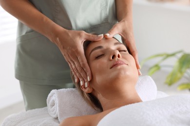 Photo of Beautiful woman receiving facial massage on couch indoors, closeup