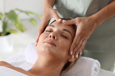 Photo of Beautiful woman receiving facial massage on couch indoors, closeup