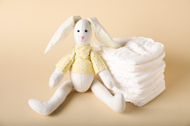 Photo of Toy bunny and diapers on beige background. Baby accessories