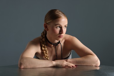 Photo of Beautiful woman with pigtail posing at table on grey background