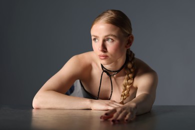 Photo of Beautiful woman with pigtail posing at table on grey background