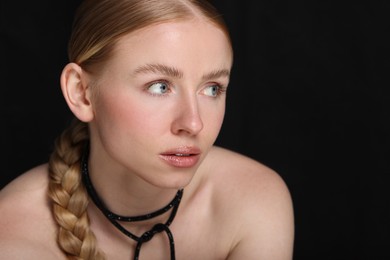 Photo of Beautiful woman with pigtail on black background, closeup