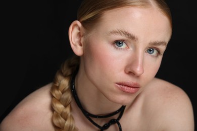 Photo of Portrait of beautiful woman with pigtail on black background, closeup