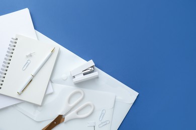 Photo of White stationery on blue background, flat lay. Space for text