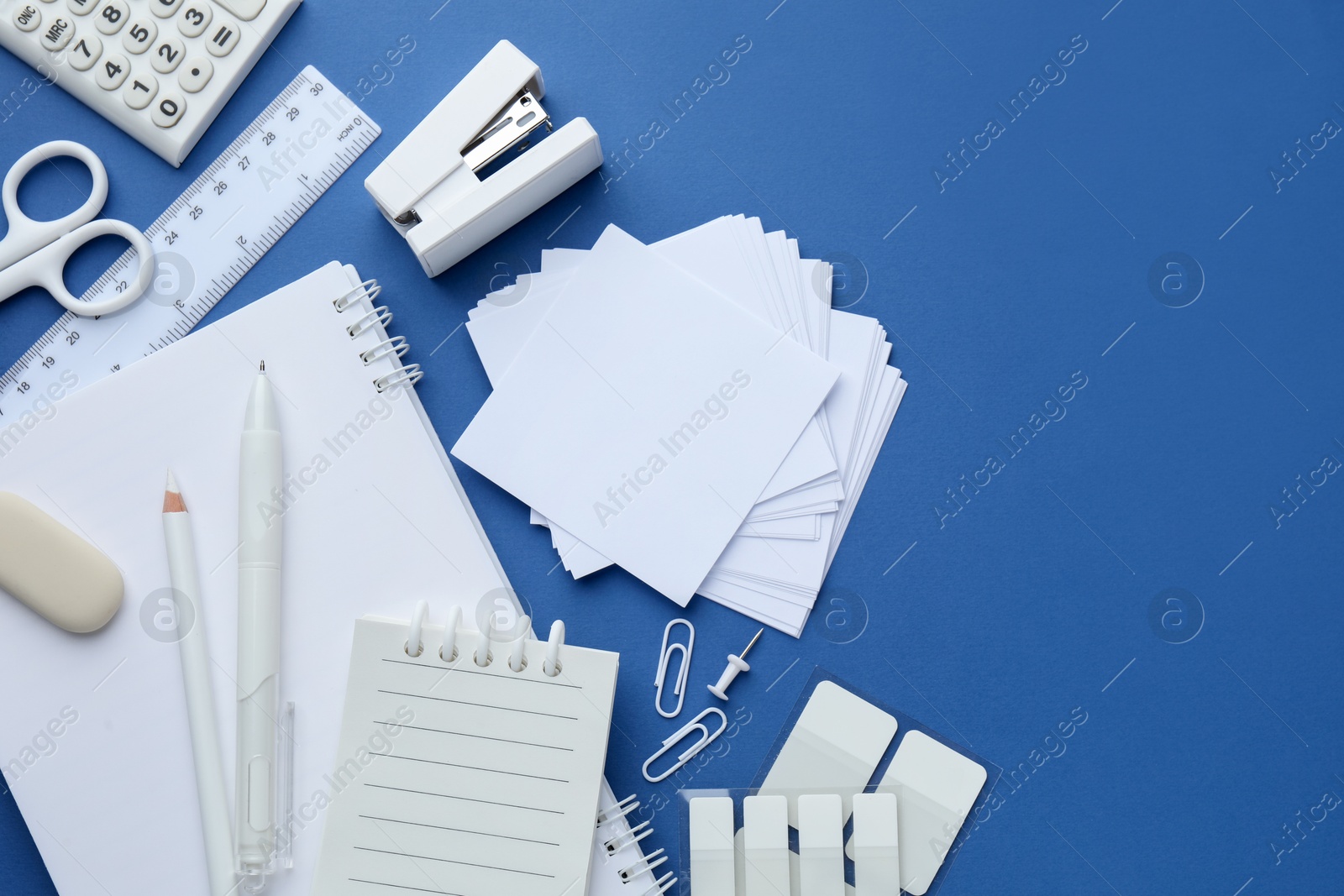 White stationery on blue background, flat lay. Space for text Photo of White stationery on blue background, flat lay. Space for text