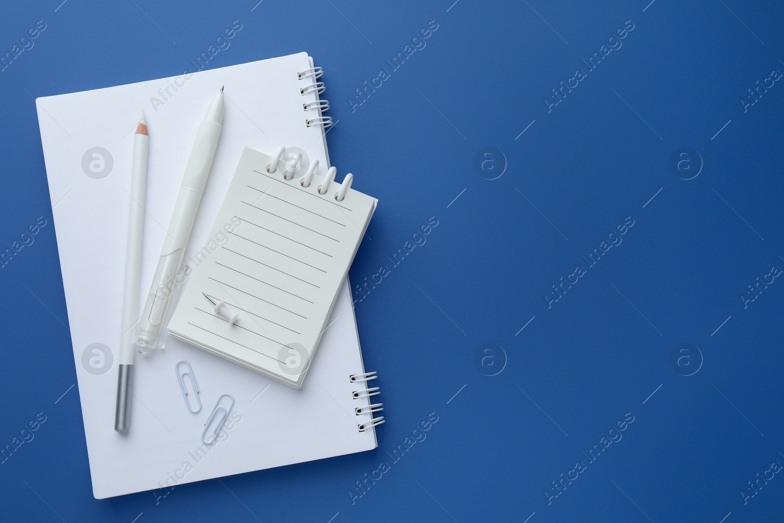 White stationery on blue background, flat lay. Space for text Photo of White stationery on blue background, flat lay. Space for text