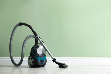 Photo of One vacuum cleaner on floor near green wall. Space for text