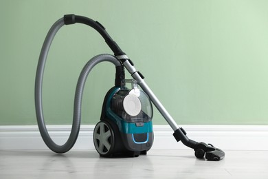 Photo of One vacuum cleaner on floor near green wall