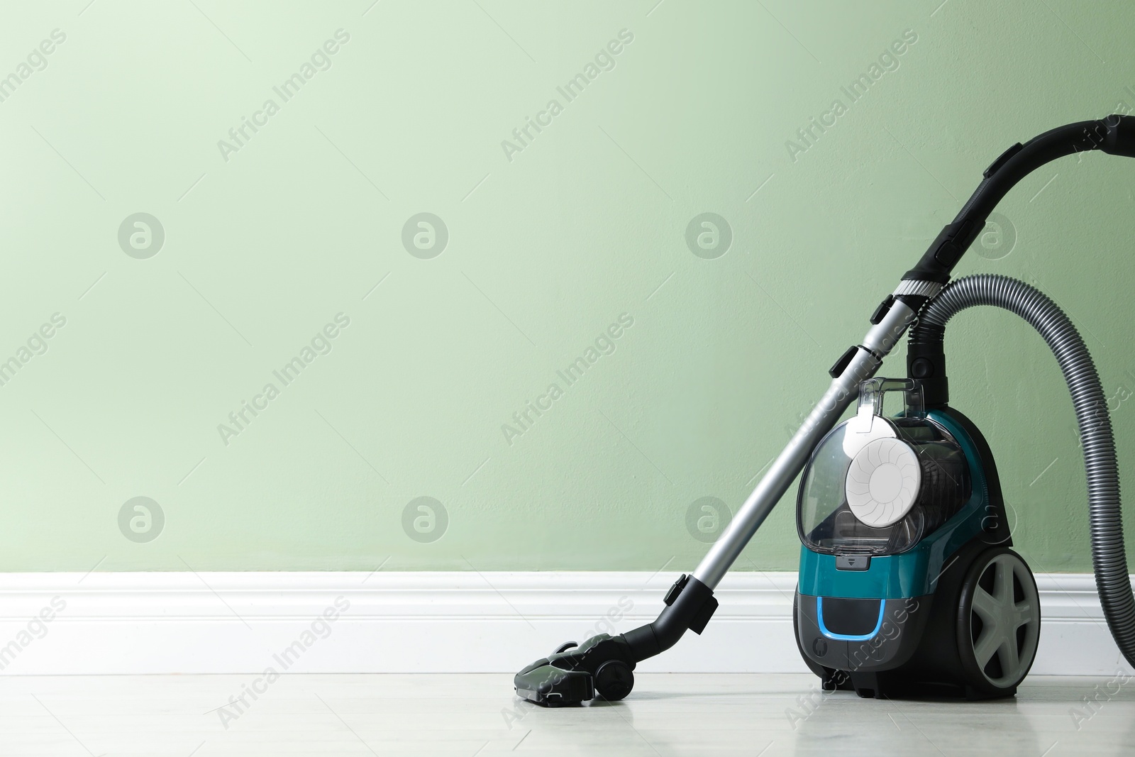 One vacuum cleaner on floor near green wall. Space for text Photo of One vacuum cleaner on floor near green wall. Space for text