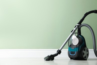 Photo of One vacuum cleaner on floor near green wall. Space for text