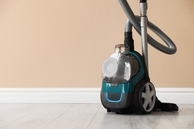 Photo of One vacuum cleaner on floor near beige wall. Space for text