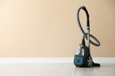 Photo of One vacuum cleaner on floor near beige wall. Space for text