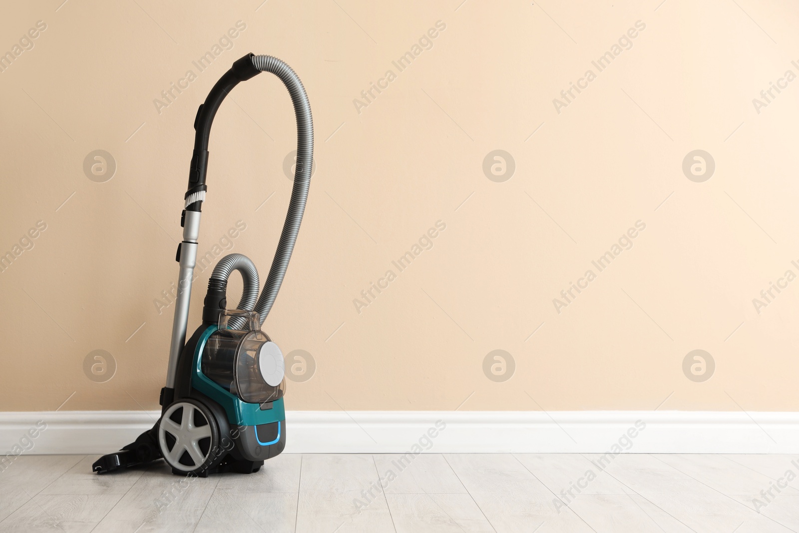 One vacuum cleaner on floor near beige wall. Space for text Photo of One vacuum cleaner on floor near beige wall. Space for text