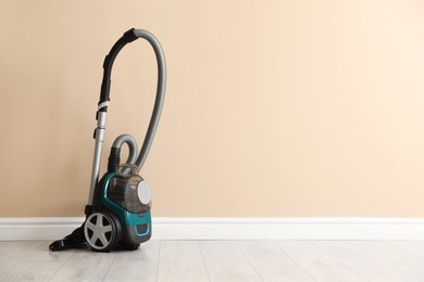 Photo of One vacuum cleaner on floor near beige wall. Space for text