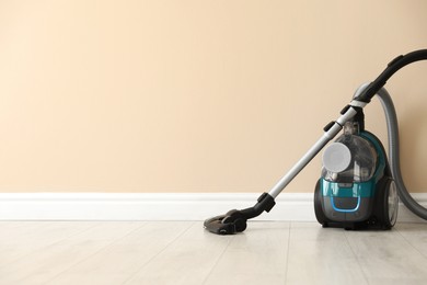 Photo of One vacuum cleaner on floor near beige wall. Space for text