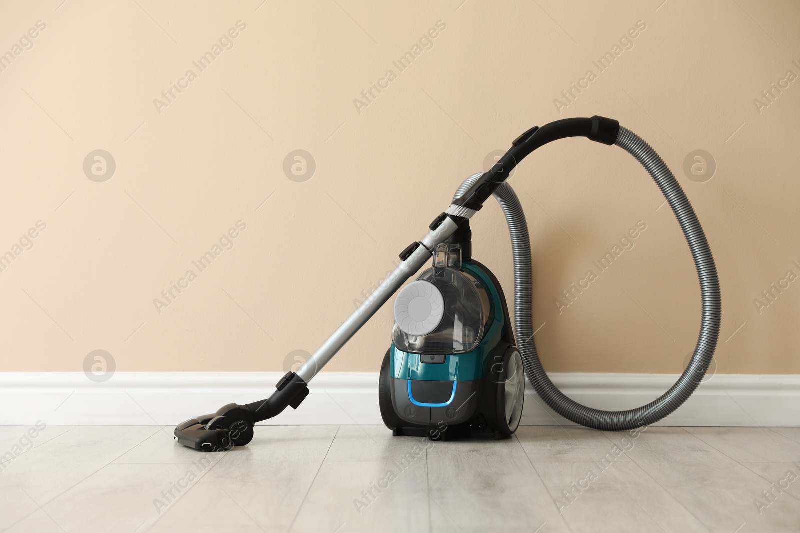 One vacuum cleaner on floor near beige wall Photo of One vacuum cleaner on floor near beige wall