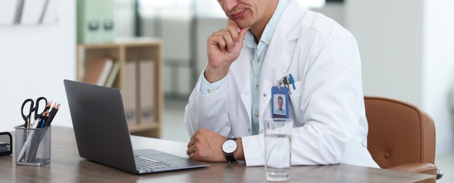 Photo of Telemedicine. Doctor having video call with patient via laptop indoors, closeup