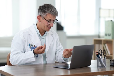 Photo of Telemedicine. Doctor having video call with patient via laptop indoors