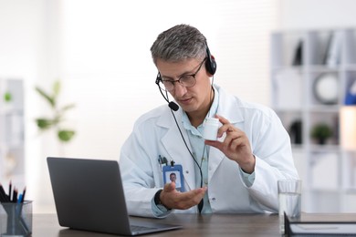 Photo of Telemedicine. Doctor recommending pills to patient during video call via laptop indoors