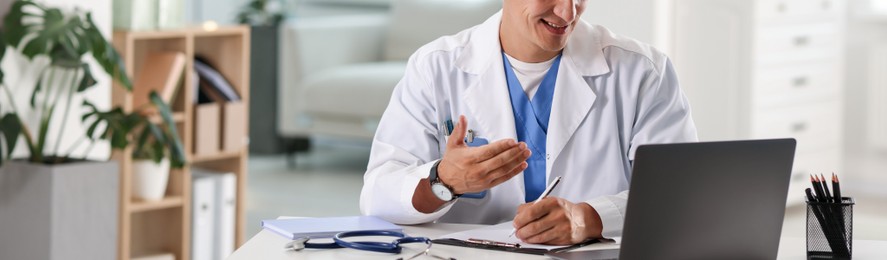 Photo of Telemedicine. Doctor having video call with patient via laptop indoors, closeup