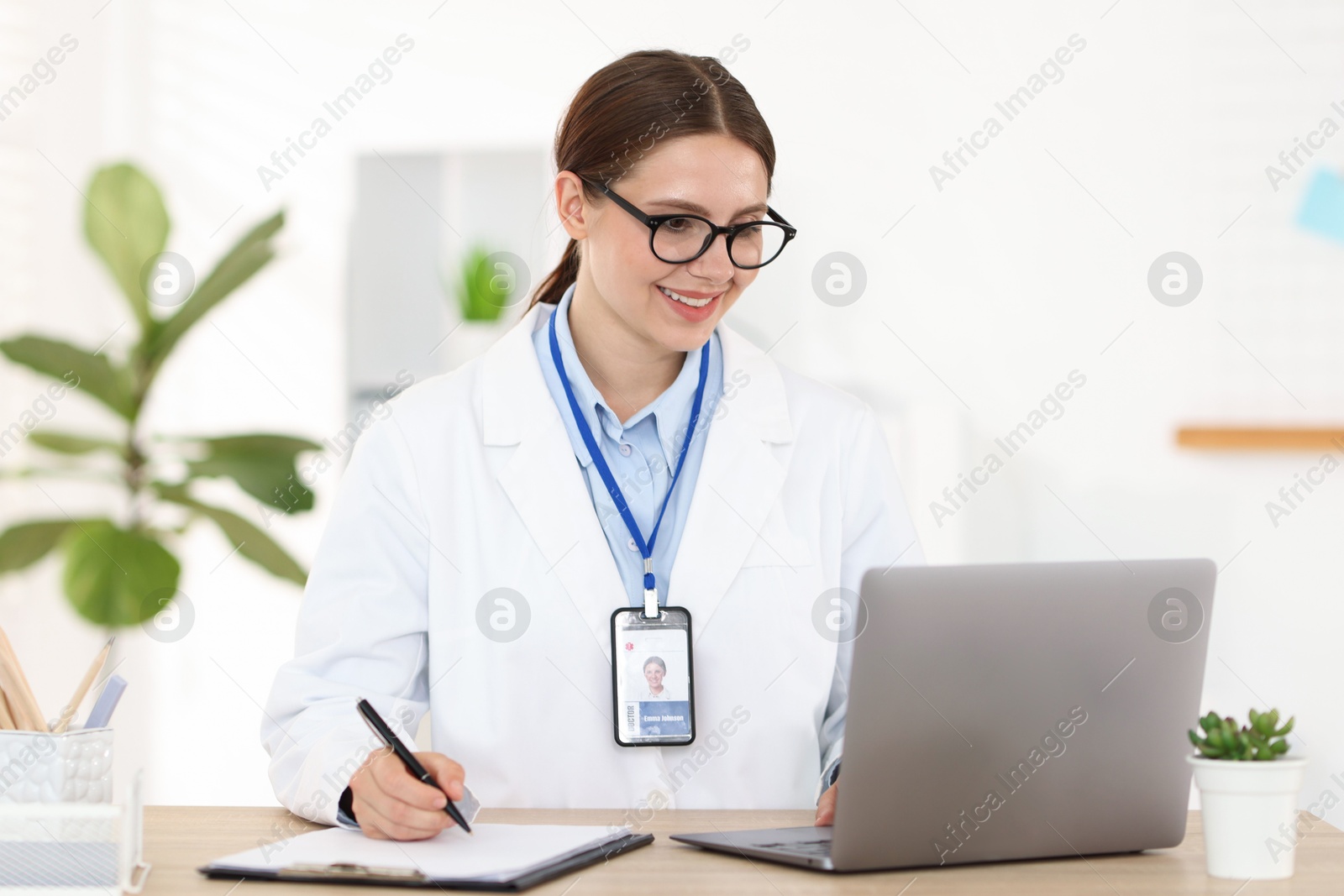Telemedicine. Doctor making notes while having video call with patient via laptop indoors Photo of Telemedicine. Doctor making notes while having video call with patient via laptop indoors