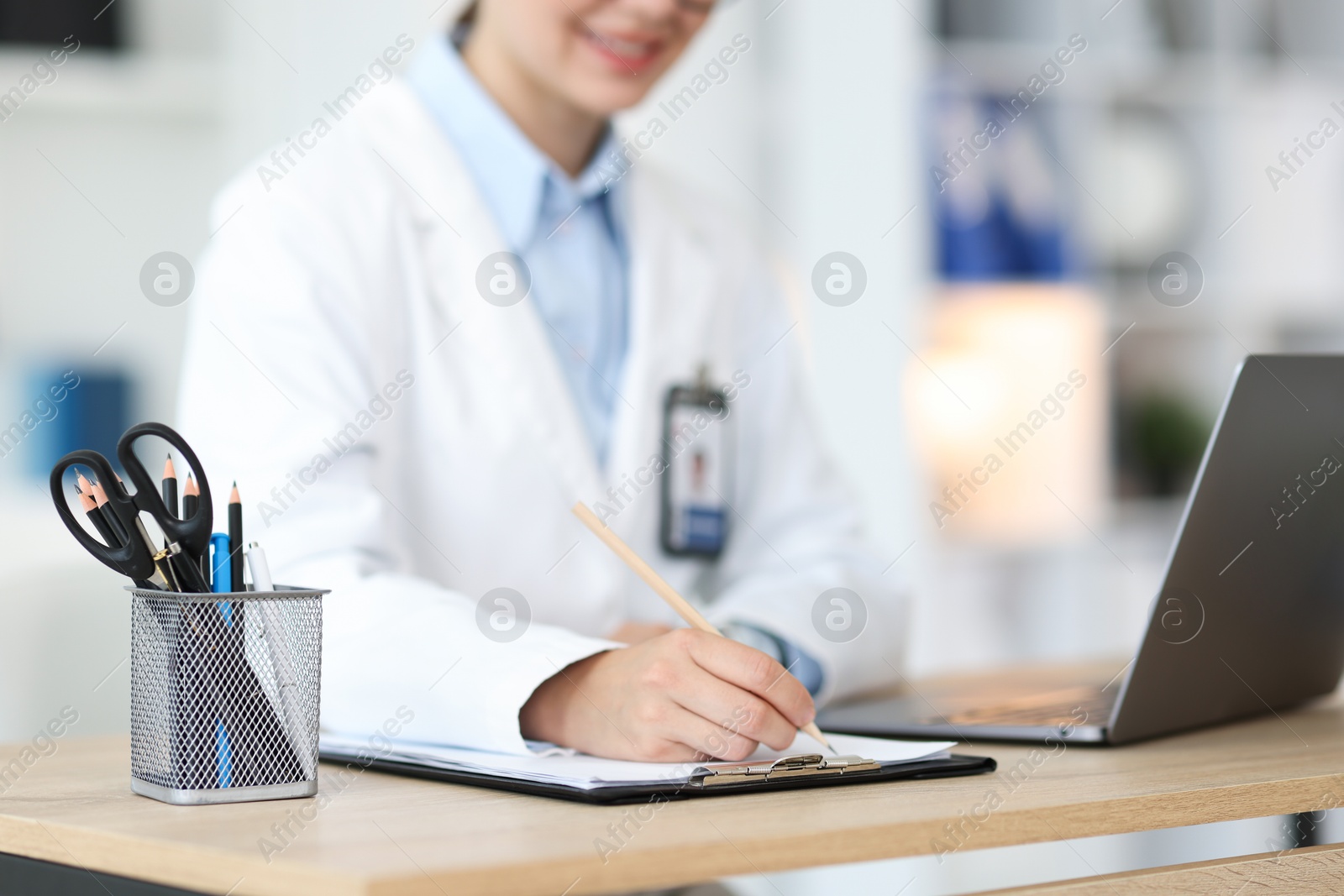 Telemedicine. Doctor making notes while having video call with patient via laptop indoors, closeup Photo of Telemedicine. Doctor making notes while having video call with patient via laptop indoors, closeup