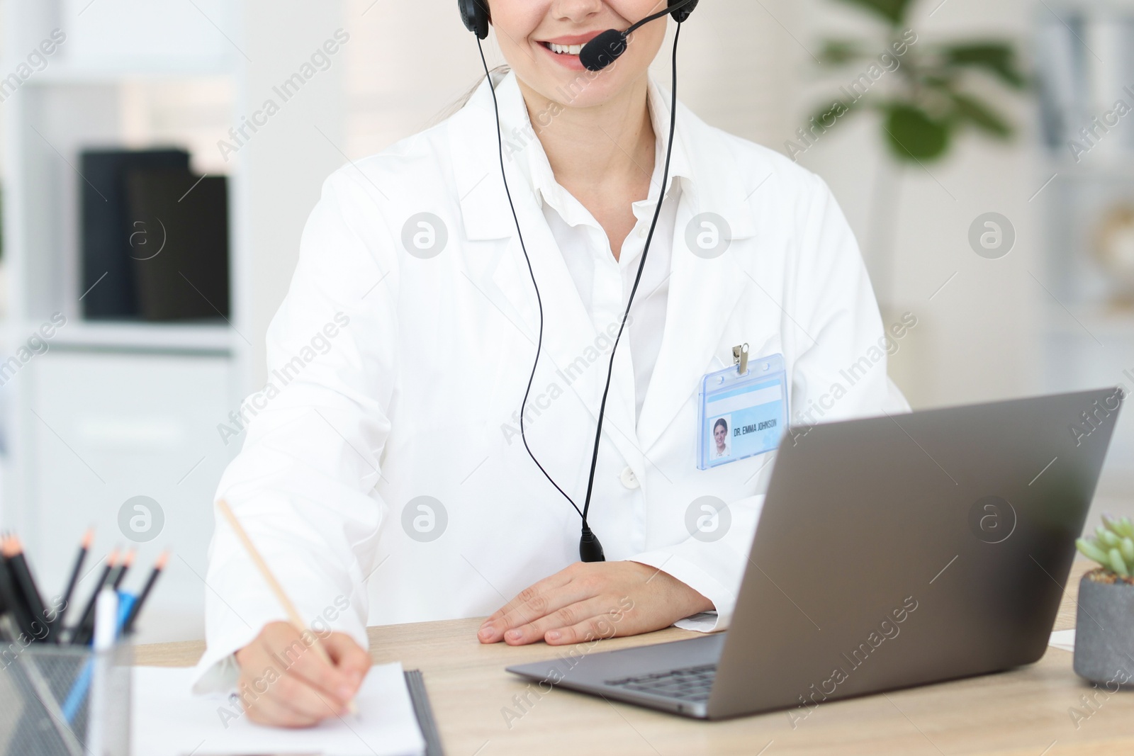 Telemedicine. Doctor making notes while having video call with patient via laptop indoors, closeup Photo of Telemedicine. Doctor making notes while having video call with patient via laptop indoors, closeup
