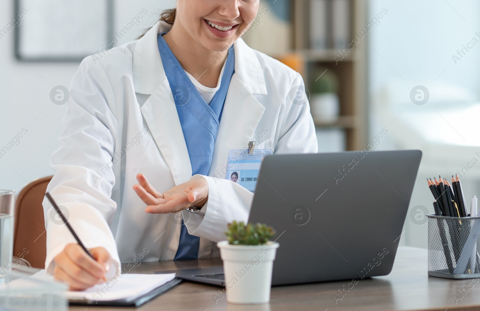 Telemedicine. Doctor making notes while having video call with patient via laptop indoors, closeup Photo of Telemedicine. Doctor making notes while having video call with patient via laptop indoors, closeup