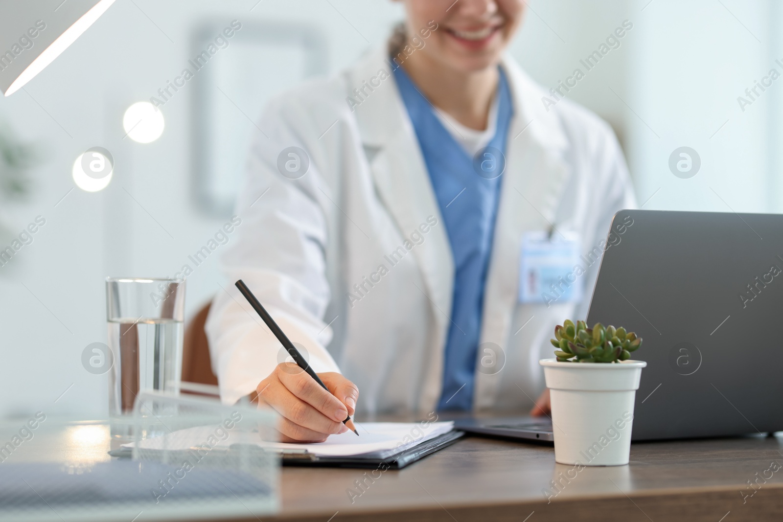 Telemedicine. Doctor making notes while having video call with patient via laptop indoors, closeup Photo of Telemedicine. Doctor making notes while having video call with patient via laptop indoors, closeup