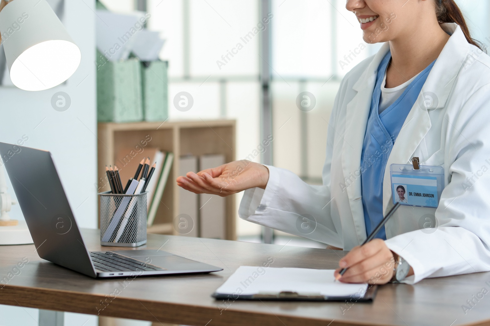 Telemedicine. Doctor making notes while having video call with patient via laptop indoors, closeup Photo of Telemedicine. Doctor making notes while having video call with patient via laptop indoors, closeup