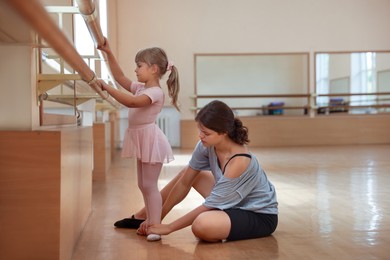 Photo of Little girl and her teacher training in barre studio