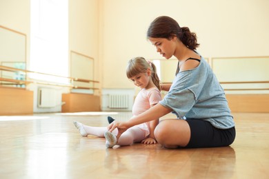 Photo of Ballet teacher working with little girl on floor in dance class