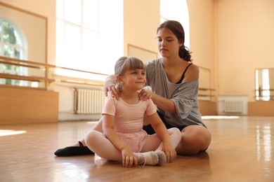 Photo of Ballet teacher working with little girl on floor in dance class