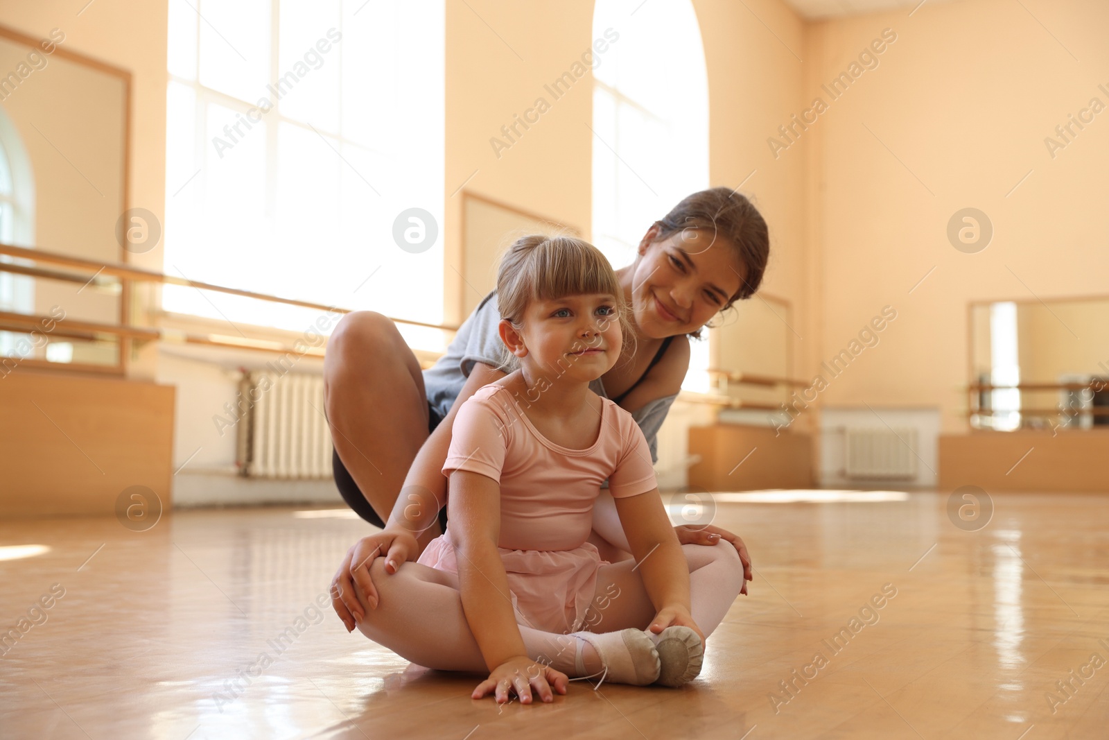 Photo of Ballet teacher working with little girl on floor in dance class