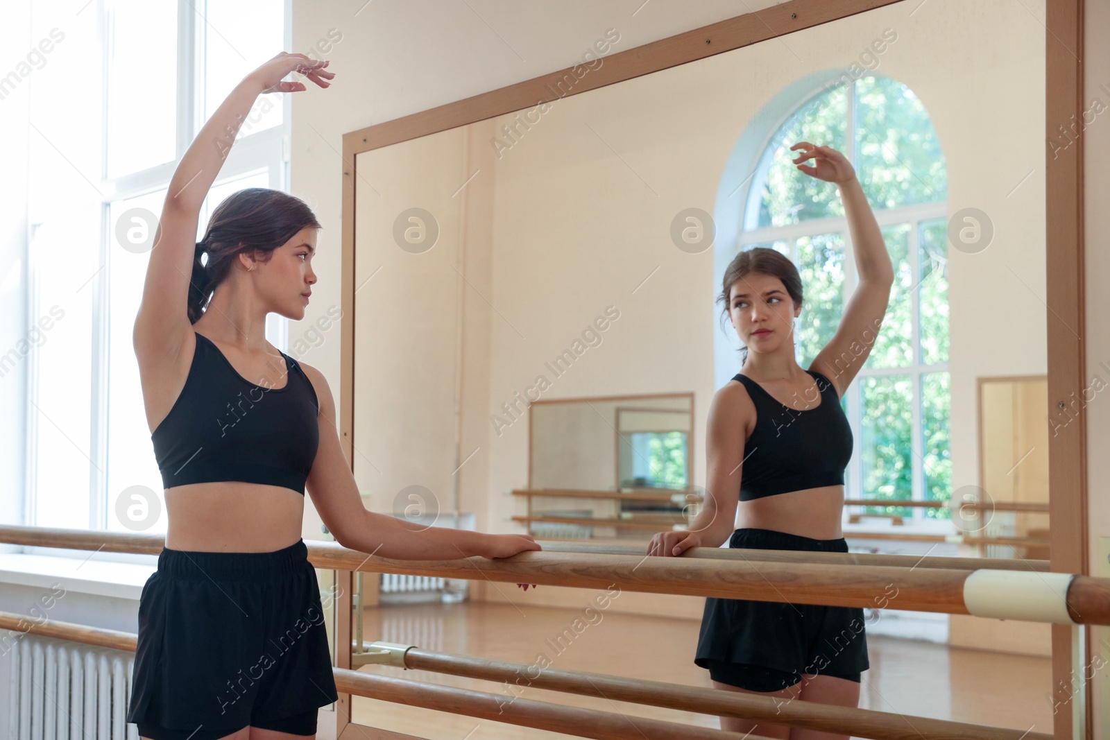 Photo of Teenage girl training near mirror in barre studio