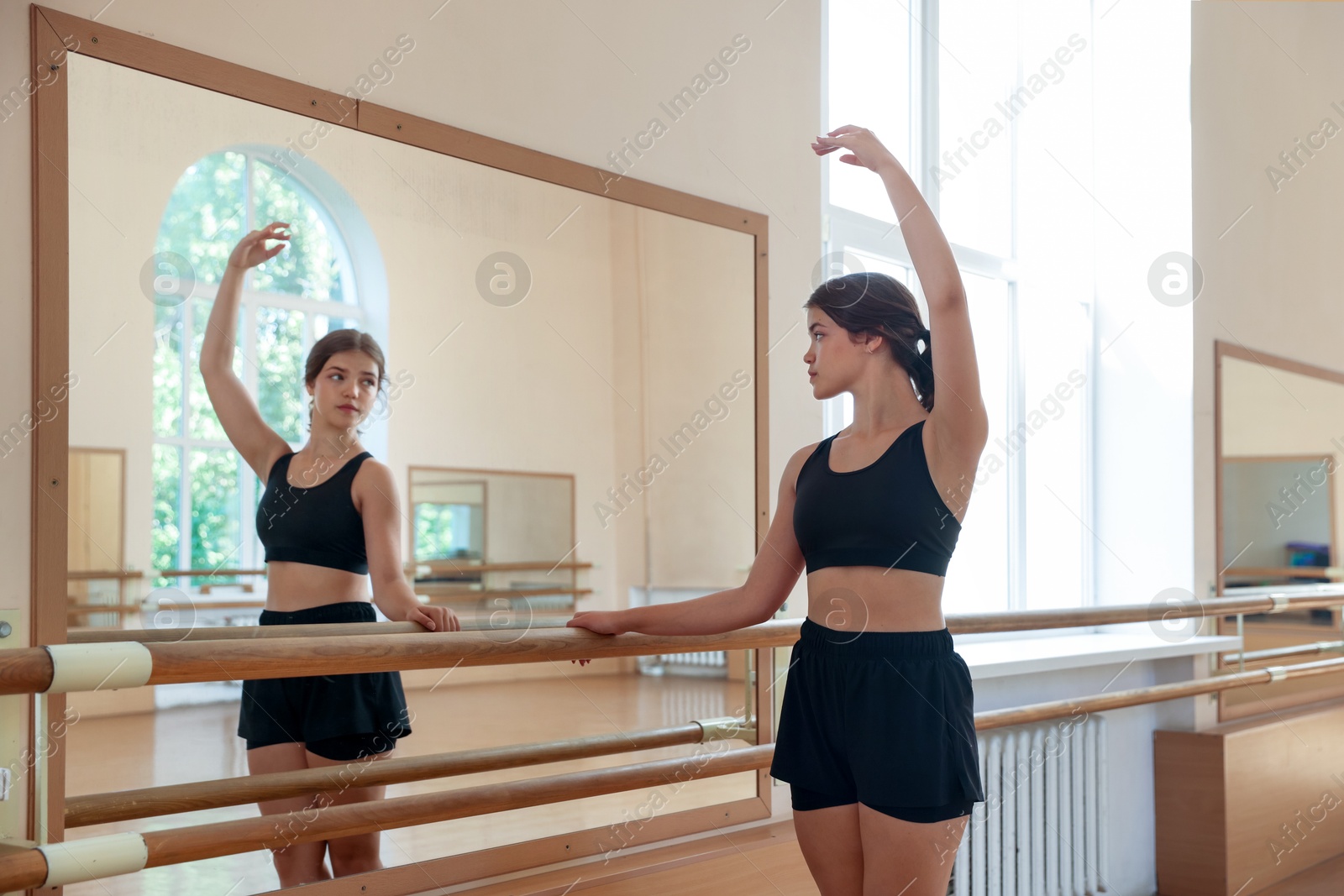 Teenage girl training near mirror in barre studio Photo of Teenage girl training near mirror in barre studio