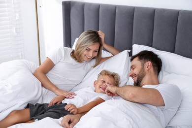 Photo of Happy family spending time together on bed at home
