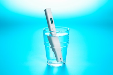 Photo of Nitrate tester in glass of water on light blue background