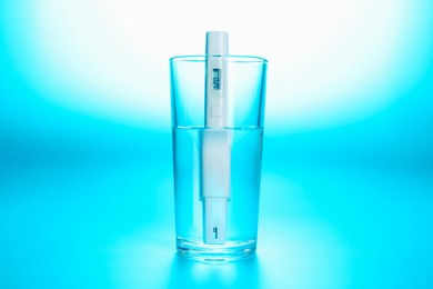 Photo of Nitrate tester in glass of water on light blue background