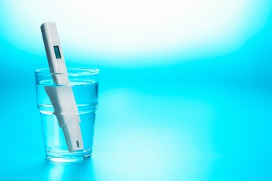 Photo of Nitrate tester in glass of water on light blue background, closeup. Space for text