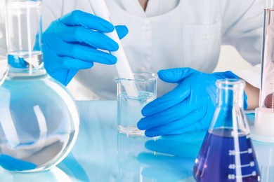 Photo of Scientist examining water with nitrate tester at white table in laboratory, closeup