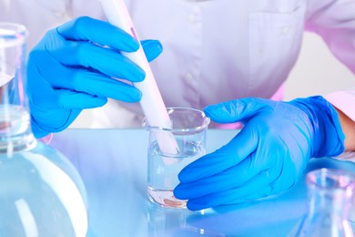 Photo of Scientist examining water with nitrate tester at white table in laboratory, closeup